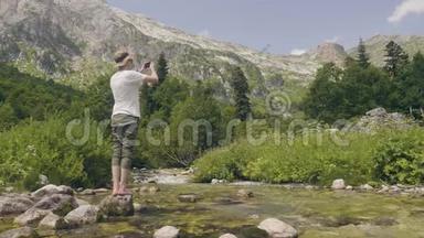 旅游人员在旅游时用手机拍摄山河景观